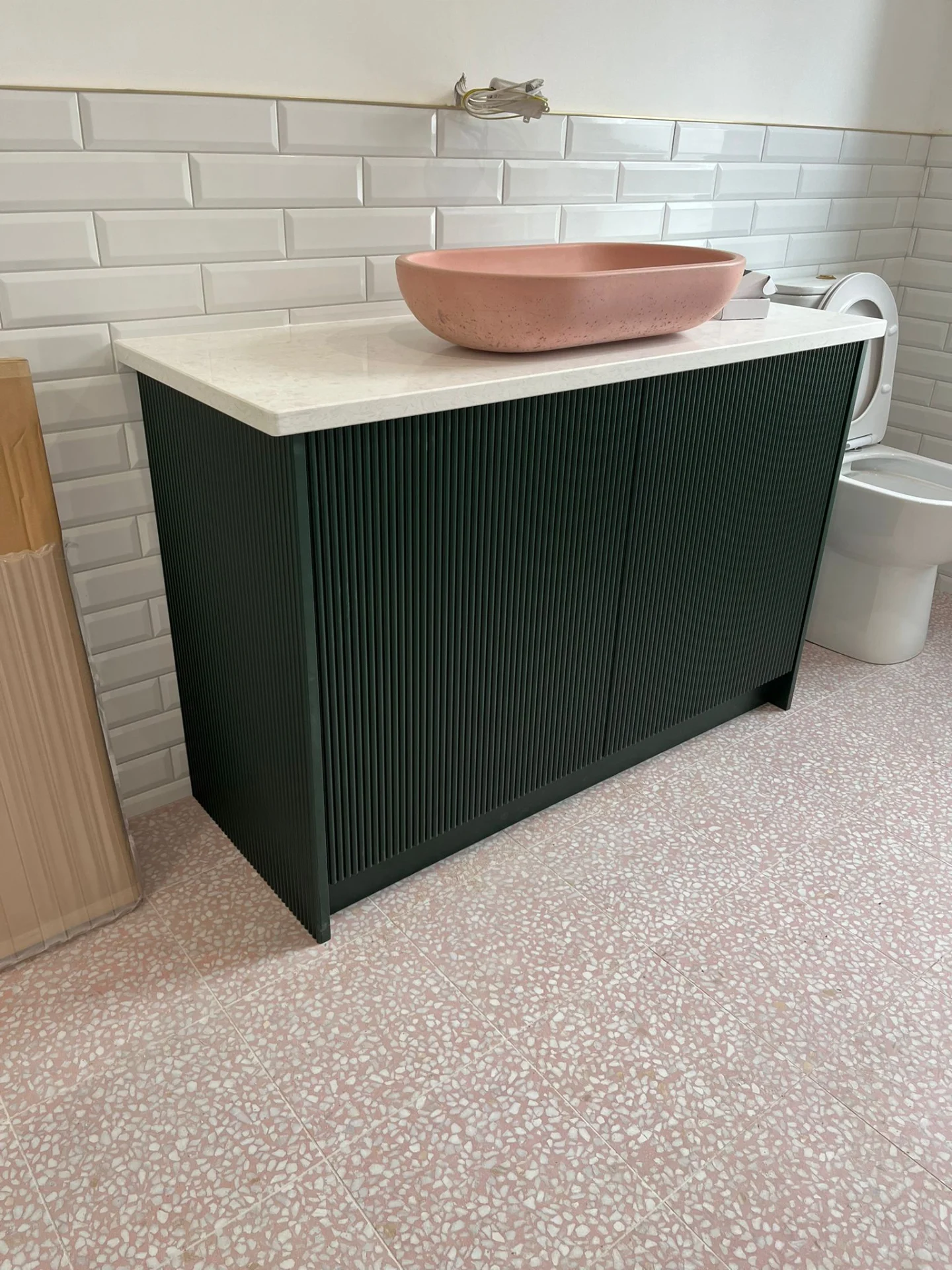 Green fluted bespoke bathroom vanity with fitted storage and stone top.