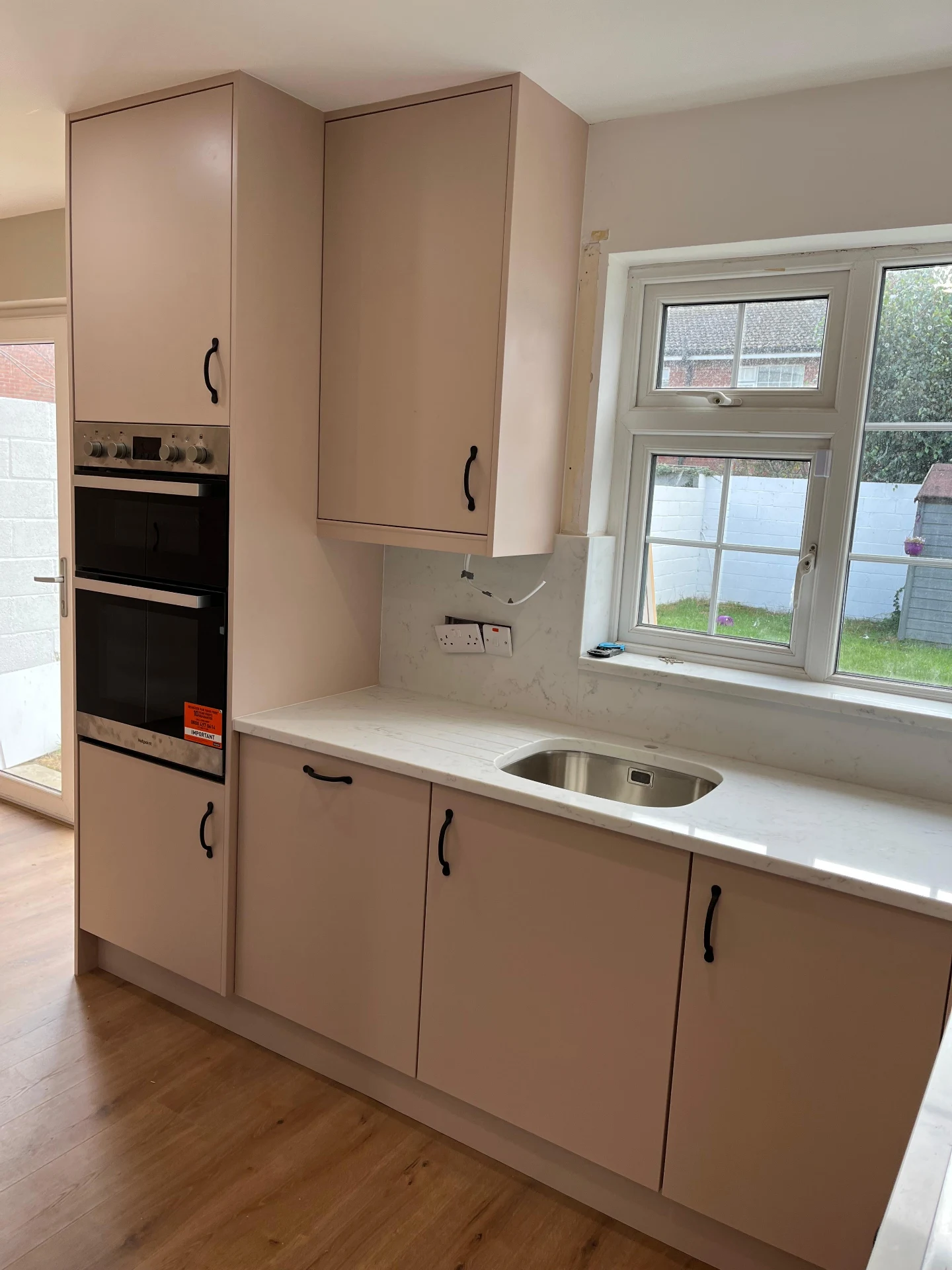 Sage utility room cabinetry with fitted sink storage, drawers and worktop.