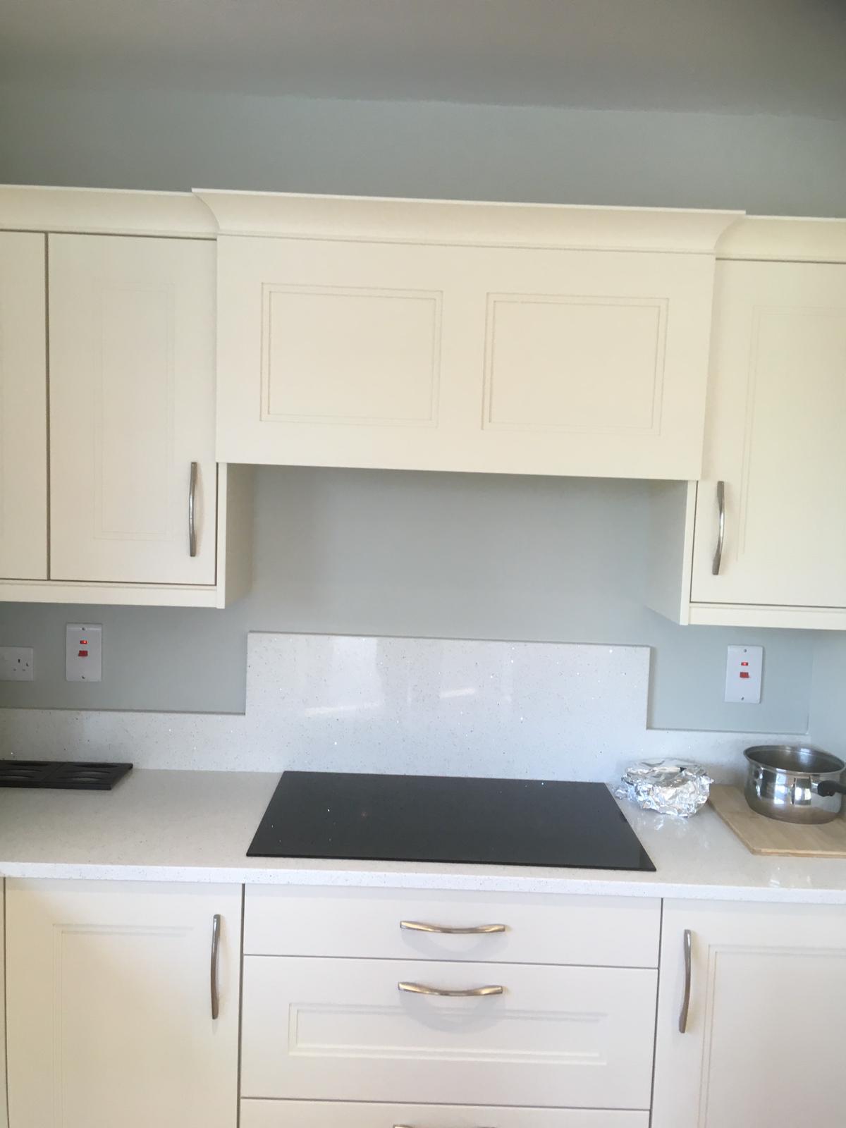 White kitchen cooking area with black cooktop and custom extractor hood.