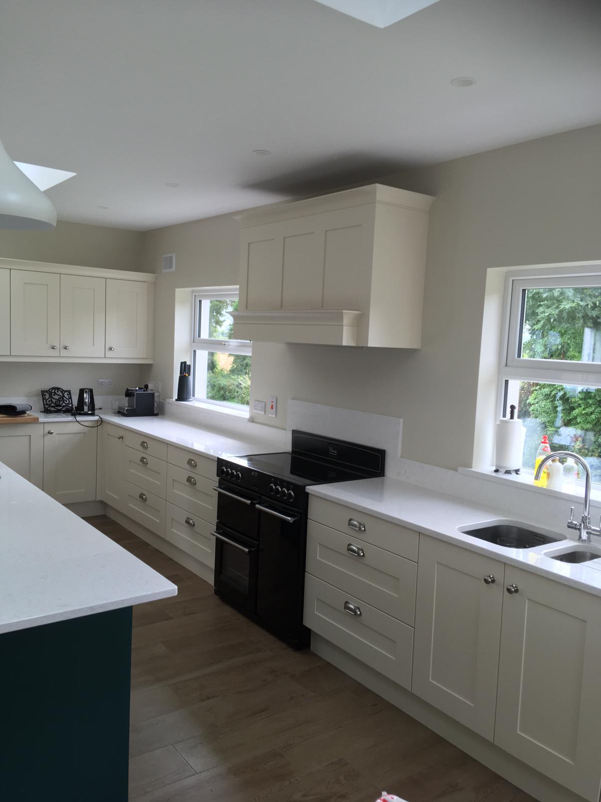 White fitted kitchen cooking area with teal island edge in the foreground.